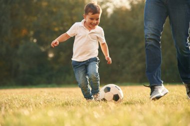 Saha manzarası, futbol topuyla. Baba ve küçük oğlu dışarıda oynuyor ve eğleniyorlar..