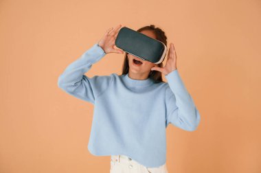 Sanal gerçeklik deneyimiyle, gözlüklerle şok oldum. Şirin genç kız stüdyoda arka planda..