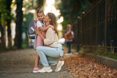 Çocuk arka planda duruyor. İki çocuklu bir kadın okula gidiyor, eğitim anlayışı..