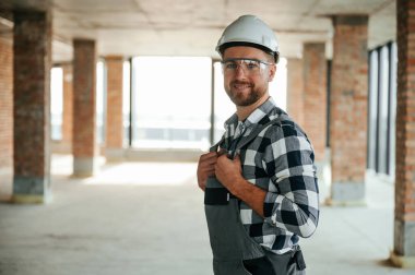 Bitmemiş odada üniformalı, gülümseyen olumlu bir inşaat işçisi..