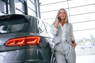 Telefonla konuşuyorum. Resmi kıyafetli kadın araba galerisinde..