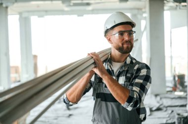 Plastik tüpler ellerinde. Bitmemiş odada üniformalı inşaat işçisi..