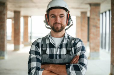 Kasketli bir portre. Bitmemiş odada üniformalı inşaat işçisi..