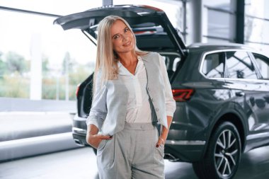 Kaput açıldı. Resmi kıyafetli kadın araba galerisinde..