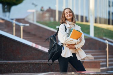 Durup poz vermek. Gündelik giysiler içinde genç bir kız öğrenci dışarıda..
