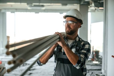 Plastik tüpler ellerinde. Bitmemiş odada üniformalı inşaat işçisi..