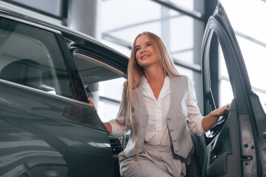Kadın araba galerisindeki modern otomobilin yanında..