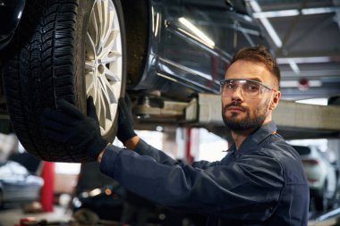 Kameraya bakıyorum. Araba tamircisi otomobille garajda..