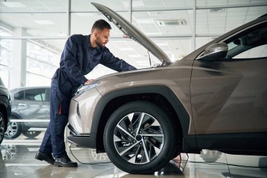 Aracı tamir ediyorum. Yan görüş. Araba tamircisi otomobille garajda..