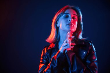 Koyu mavi arka plana karşı. Neon renkli güzel bir kadın portresi..