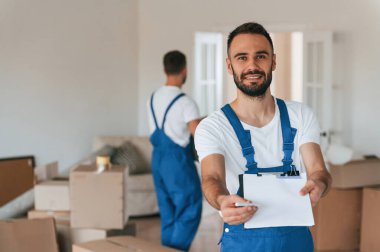 Belgeleri imzalayın. Bir odada hareket eden iki servis çalışanı.