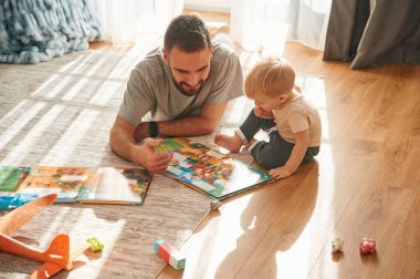 Ön manzara. Adam evcil odasında oğluyla oynuyor..