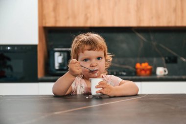 Mutfakta yoğurt yiyen küçük şirin bir çocuğun portresi..
