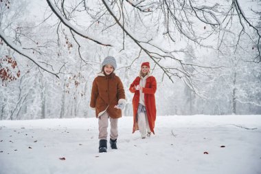 İleri koşuyor. Anne ve kızı kış çayırlarında ve ormandalar..