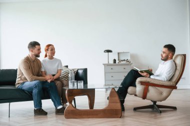 Adam notlar yazıyor. Psikolog randevusundaki çift..