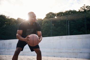 Doğal ışıklandırma. Genç siyah adam basketbol topuyla dışarıda..