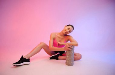 İyi olmak, silindirli. Spor elbiseli genç kadın stüdyoda arka planda karşı karşıya.