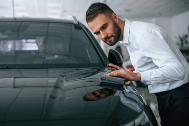 Cilalı yüzeye bakıyorum. Resmi giyinen işçi oto kuaföründe..