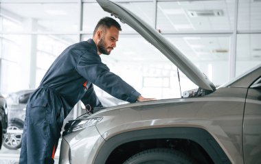 Aracı tamir ediyorum. Yan görüş. Araba tamircisi otomobille garajda..