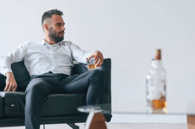 Elde bir bardak viski. Alkolik genç adam içeride..