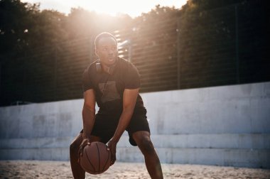 Topu elinde tutuyor. Genç siyah adam.