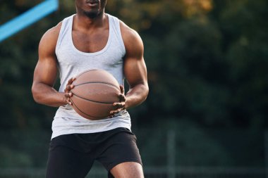 Ön manzara. Genç siyah adam basketbol topuyla dışarıda..