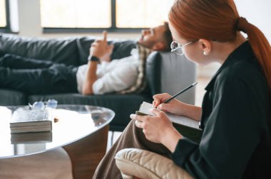 Kanepeye uzanıyordu. Erkek, kadın psikologla terapi seansında..