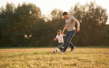 Aktivite, koşmak ve futbol oynamak. Baba ve küçük oğlu dışarıda oynuyor ve eğleniyorlar..