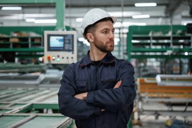 Makineye karşı. Fabrika işçisi kasketli bir şekilde içeride..