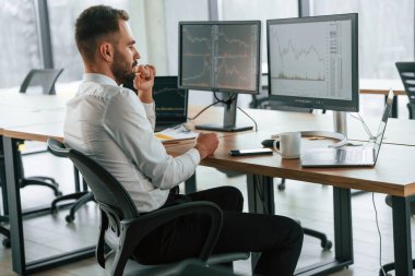 Yan görüş. İşadamı bilgisayar başında oturuyor ve ofiste çalışıyor..