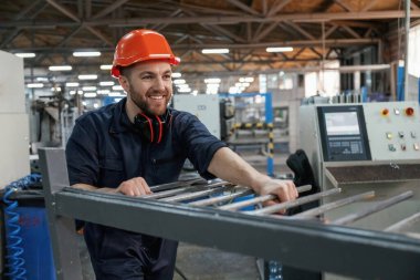 Makinelerle çalışmak. Fabrika işçisi kasketli bir şekilde içeride..