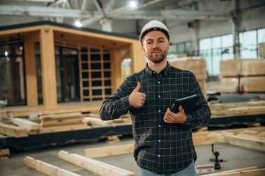 Dijital tablet hazır. Erkek müteahhit ahşap ev inşaatında..