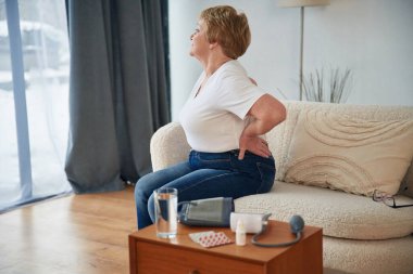 Sırt ağrısı. Yaşlı yaşlı kadın evde, oturma odasında..