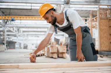 Kalas kalas işaretliyorum. Ahşap depoda sanayi işçisi..