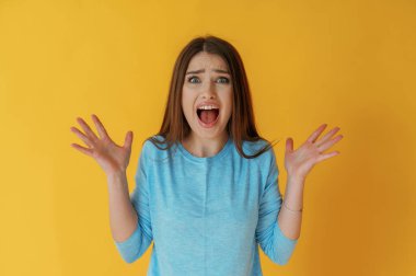 Şok ya da beklenti çığlıkları, el hareketi. Genç bayan sarı arka plana karşı..