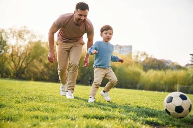 Futbol maçı. Topla. Mutlu baba ve oğul yazın sahada eğleniyorlar..
