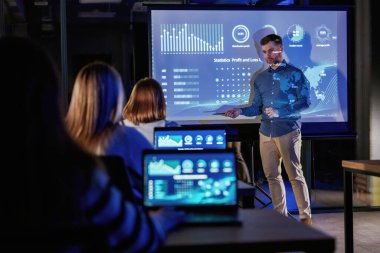 Şirketin büyümesine yardım etmek. Erkek işletme eğitmeni projektöre karşı, insanlara öğretiyor..