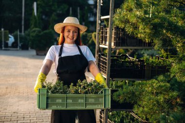 Genç kızıl saçlı kadın bahçeyle ilgileniyor..