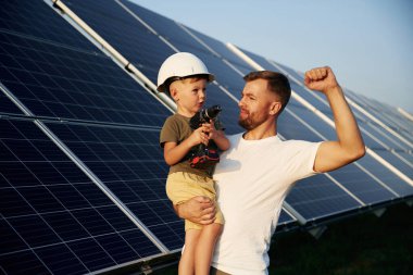 Beyaz başlık. Baba ve küçük oğlu güneş panellerinin yakınındalar..