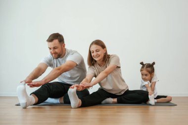Anne, baba ve kızı evde yoga yapıyor..