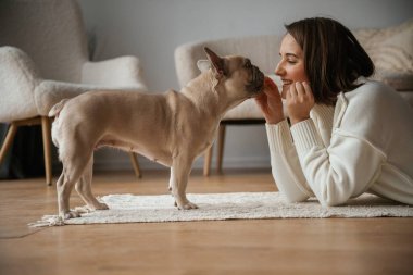 Yan taraftan bak, yere uzan. Genç kadın köpeğiyle evde..