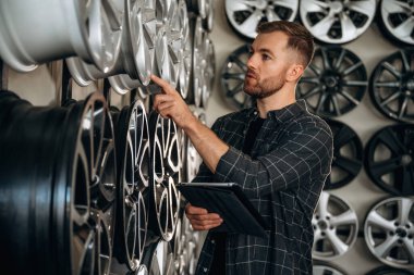 Müdür ürünü dijital tabletle kontrol ediyor. Tekerlekleri ve tekerlekleri olan tamirci var..