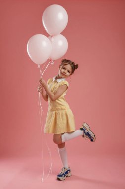 Doğum günü partisi. Balonları tutuyorum. Şirin küçük kız pembe arka plana karşı..