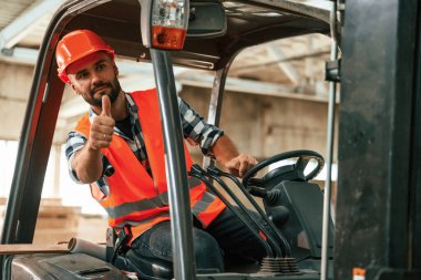 Forkliftte oturuyor. Ahşap depoda sanayi işçisi..