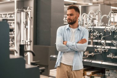 Kollarını kavuşturmuş, banyo malzemeleriyle dikiliyorsun. Adam hırdavatçıda..