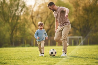 Futbol oynamayı öğreniyorum. Mutlu baba ve oğul yazın sahada eğleniyorlar..
