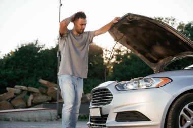 Sorun, bozuk otomobili tamir etmek ve onarmak. Adam dışarıda arabasıyla bekliyor..