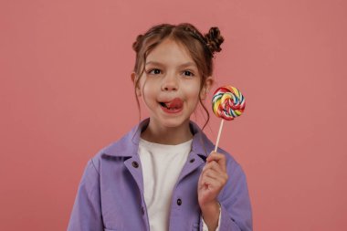 Manzarayı şekerle kapatın. Şirin küçük kız pembe arka plana karşı..