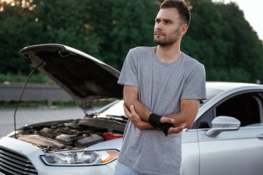 Elde ağrı, kaza, bozuk otomobil. Adam dışarıda arabasıyla bekliyor..
