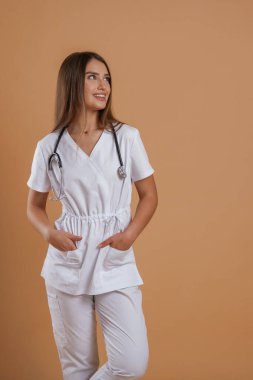 Bir hemşireden neşeli bir yüz ifadesi. Genç ve güzel bir bayan stüdyoda arka plana karşı..